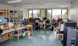 Impressionen aus der Mediothek (Kinder an PCs, Tischen und eine Spiele bzw. Bücherauswahl)